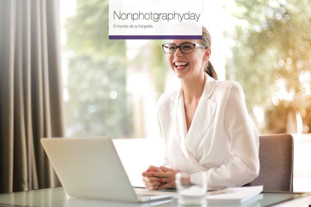 Laughing businesswoman working in office with laptop